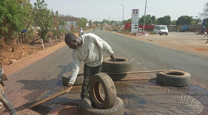 PHOTOS: Vulcanizer patches potholes along Wa-Kumasi road with tires.